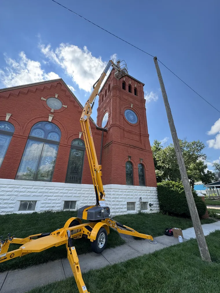 G.W. Painting boom lift raised to the bell tower of a historic brick church